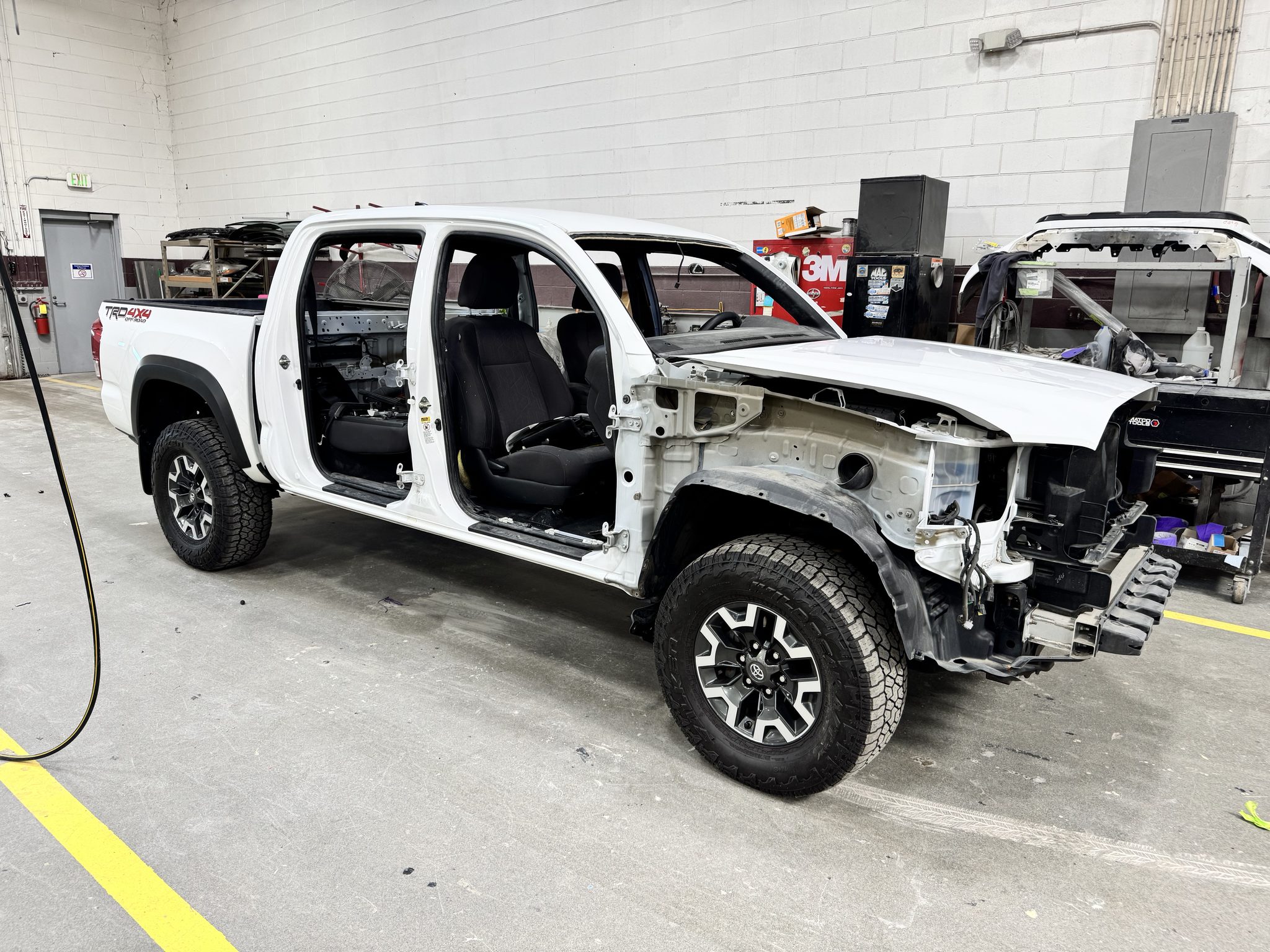 White Toyota Tacoma TRD Off-Road with all four doors removed for a Super White paint refinish under Toyota program 23TE08 at Bob Rohrman Collision Repair Center in Lafayette, Indiana