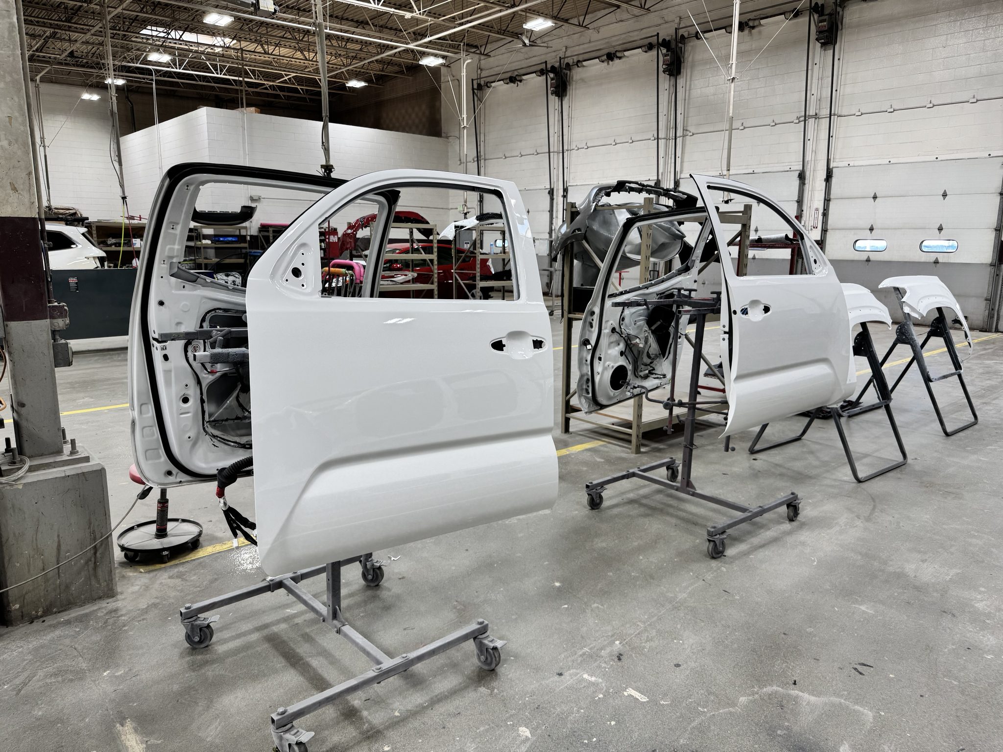 Freshly repainted Super White Toyota Tacoma doors on body stands waiting to be reinstalled at Bob Rohrman Collision Repair Center in Lafayette, Indiana